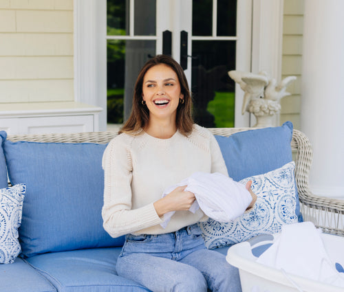 a woman sitting on a blue couch holding a white blanket