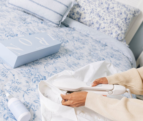 a person ironing clothes on a bed